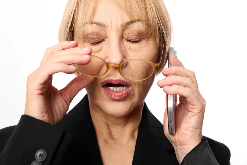 Woman businesswoman adjusts glasses while talking on smartphone, eyes closed, stress and fatigue in closeup portrait, phone communication, isolated on white background, studio light