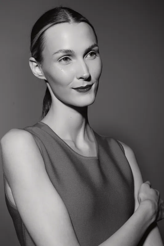 Portrait of a slender Caucasian woman with fair skin and slicked back hair wearing a sleeveless top against plain background. Concept of beauty and elegance.