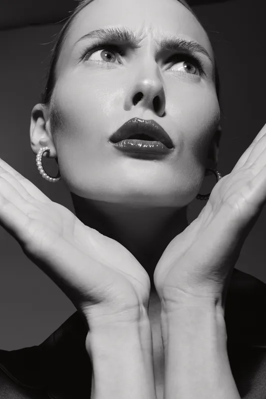 Close-up of a fair skinned Caucasian woman with dark lips and expressive face in black and white. Concept of beauty, fashion, and emotion in studio lighting.