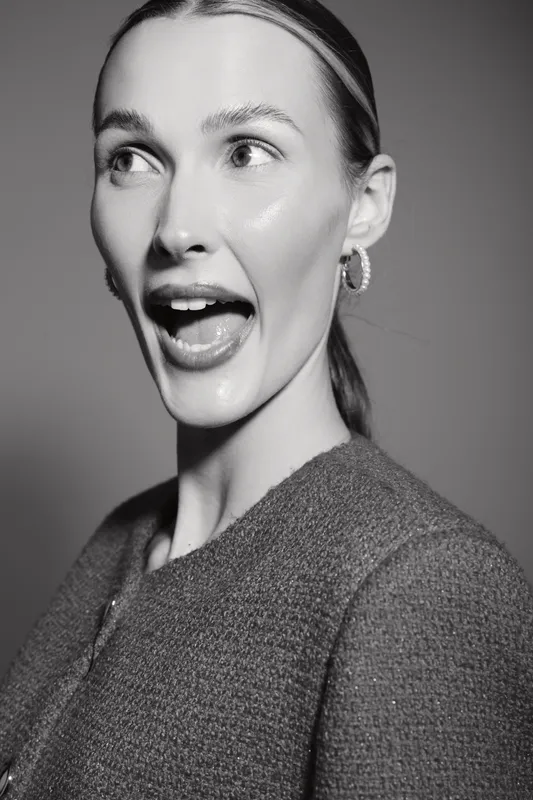 Young white woman with light skin and slicked back hair looks surprised with open mouth in black and white close-up portrait. Concept for emotion and expression.