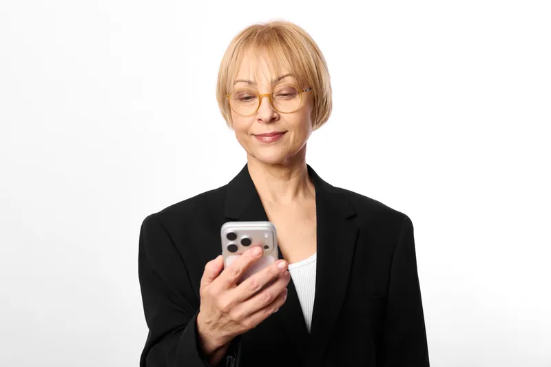 woman smartphone elderly glasses portrait communication technology, professional holding mobile, calm studio portrait with soft light on white background indoors