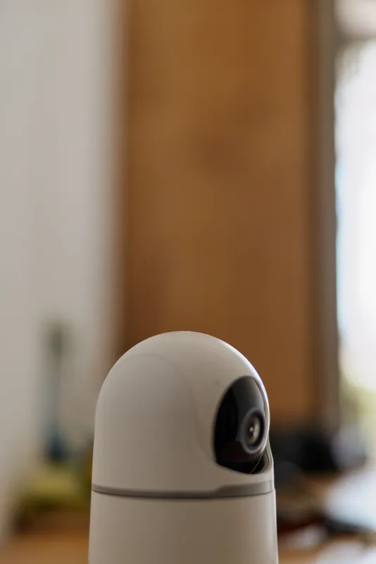 Close up of a smart home camera indoors, capturing a calm living space. This scene conveys home security, daily routine, and mindful protection. Soft lighting creates a warm, confident mood.