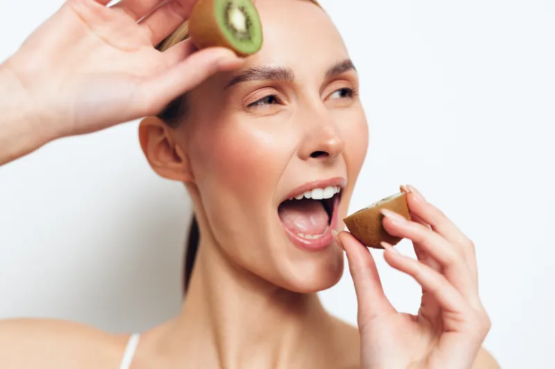 Woman avocado eating fruit closeup portrait shows healthy diet nutrition wellbeing, female with open mouth bites fresh avocado on white studio background with hands holding slice