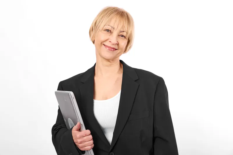 Woman senior business tablet professional smile portrait office concept, studio portrait on white background, blazer, confident stance, holding tablet, clean neutral lighting
