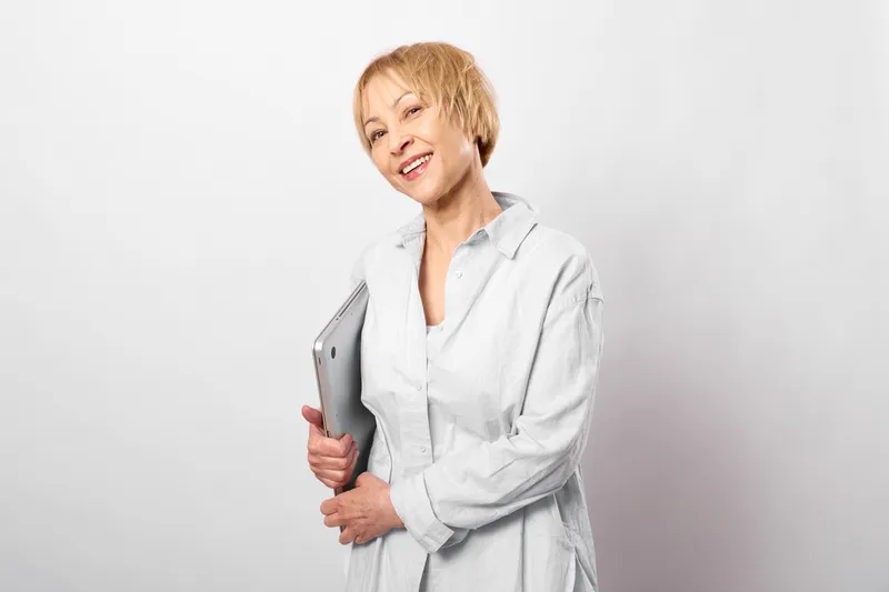 Woman in medical coat, doctor portrait, holding folder, studio gray background, serious professional expression, healthcare worker presenting documents for office work