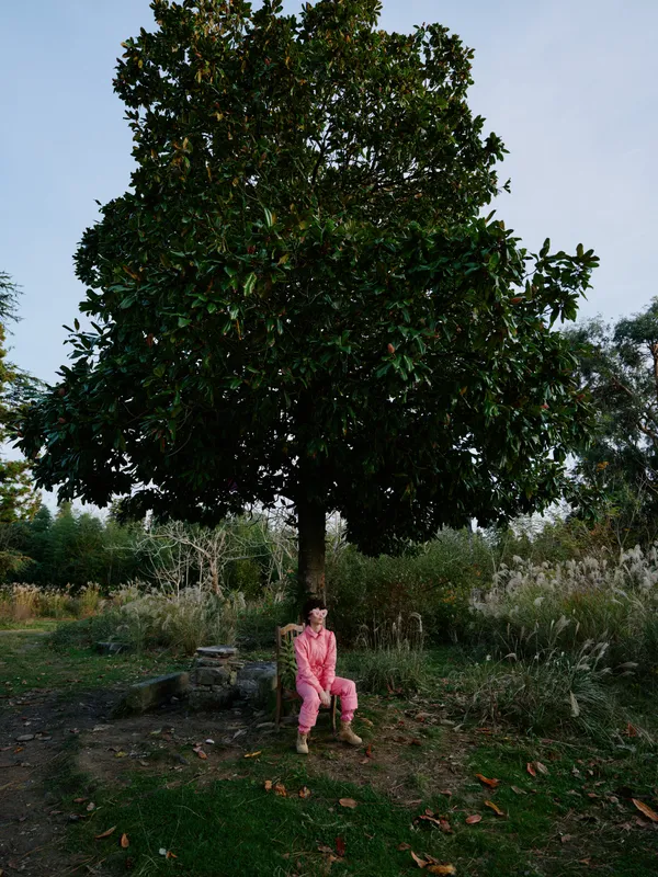 Outdoor scene with a child sitting beneath a large tree in a park, enjoying nature, shade and quiet relaxation in a peaceful outdoor setting for stock use