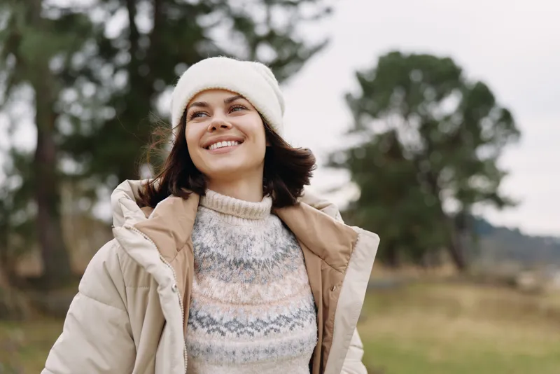 Woman outdoors smiling autumn coat jacket beanie nature landscape scenery a relaxed moment in a windy outdoor setting