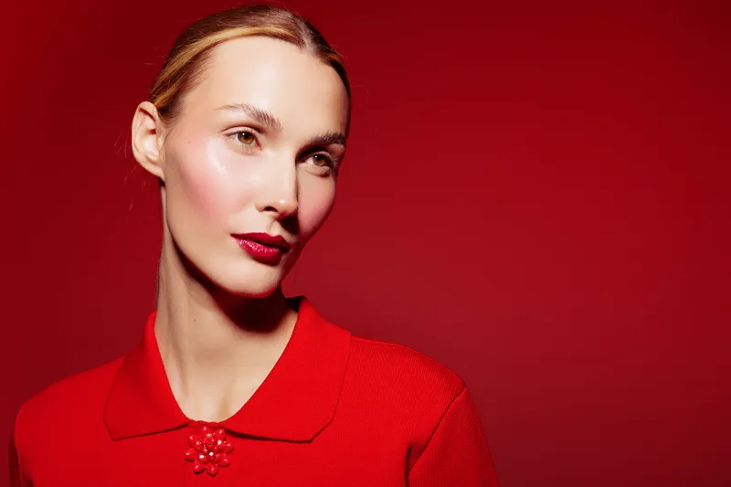 Portrait of a confident woman with red lipstick and red outfit against red background. Concept of fashion, beauty, elegance, and bold style with monochrome color scheme.