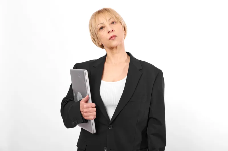 Serious businesswoman in black suit portrait holds tablet, looking tired and thoughtful, professional technology concept, isolated on white background, studio lighting