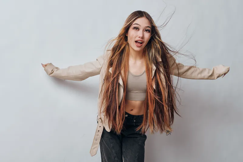 Young woman with long dreadlocks hair wearing casual clothes posing with arms spread on white background for fashion and hairstyle concept. Female model with confidence and style.