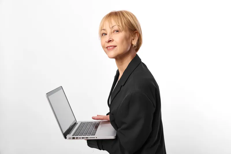 Woman business professional portrait with laptop in studio white background, confident mature woman standing in office style, remote work concept, side view, gentle smile