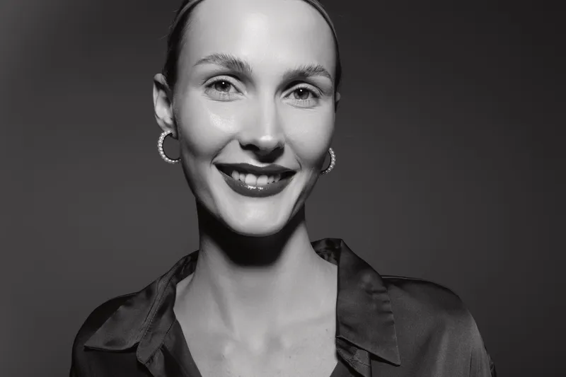 Smiling white adult woman with light skin and earrings looks at the camera in studio. Concept for beauty, confidence, and fashion portrait with black and white lighting.