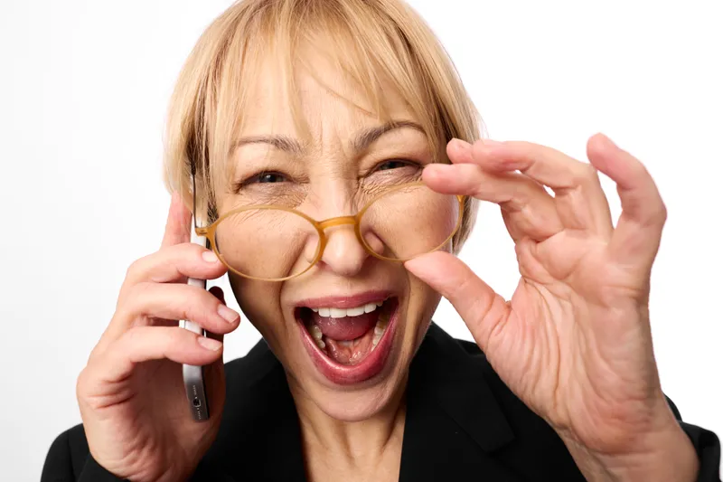 Woman glasses phone smiling surprise elderly funny communication, senior business call on white background, holding eyewear with hands, open mouth laughter, isolated portrait