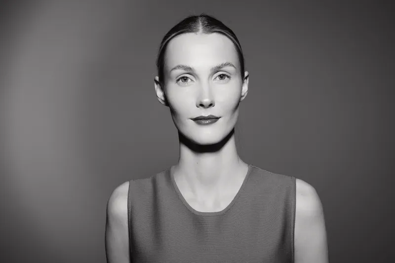 Portrait of a young Caucasian woman with light skin and tied back hair wearing a sleeveless top, looking confidently at the camera in black and white.