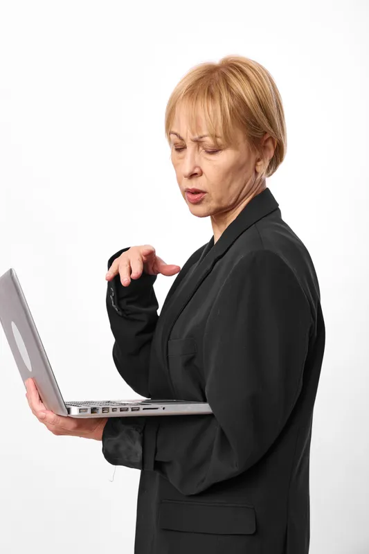 Woman with laptop, senior business working on white background, isolated studio, black blazer, focused face, typing and checking documents, professional portrait for office tasks
