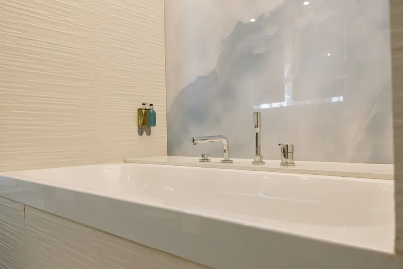 Bathroom sink with chrome faucet and white basin, modern fixture on a light wall tile panel, a compact vanity and countertop in a calm, minimalist space