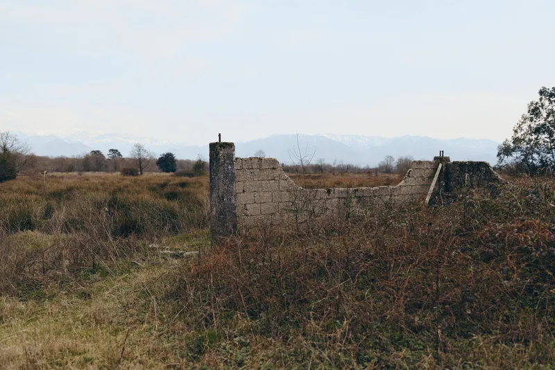 Landscape view, rural countryside with mountains in the distance, stone wall ruins in the pasture, vegetation and nature fill the field, scenery quiet outdoors travel lifestyle