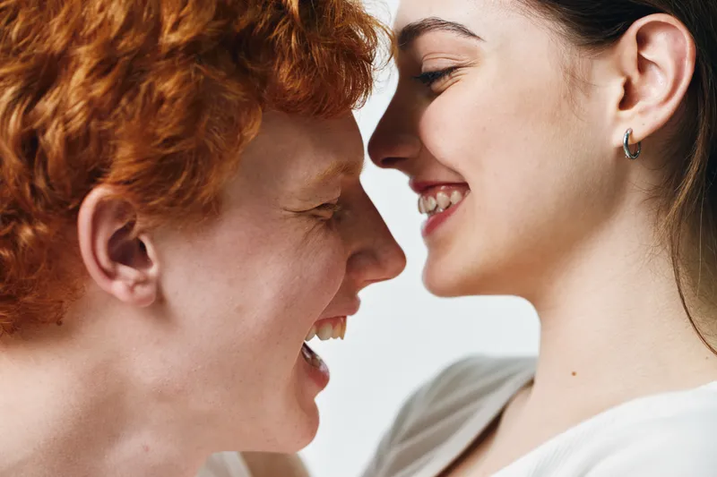 Two women smiling face to face in close up with happy expression, joy and connection between people, friendship and positive emotions in studio.