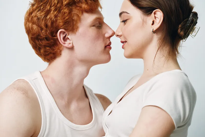 Couple, young man and woman facing each other closely for intimacy, connection and affection with closed eyes and peaceful expressions in casual clothing.