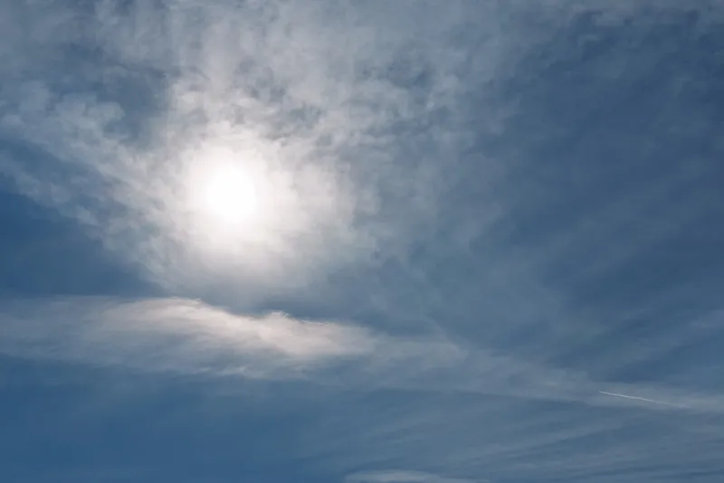 Clear sky with bright sun and wispy clouds, showcasing daytime weather, blue tones and wide outdoor atmosphere with gentle light and peaceful openness