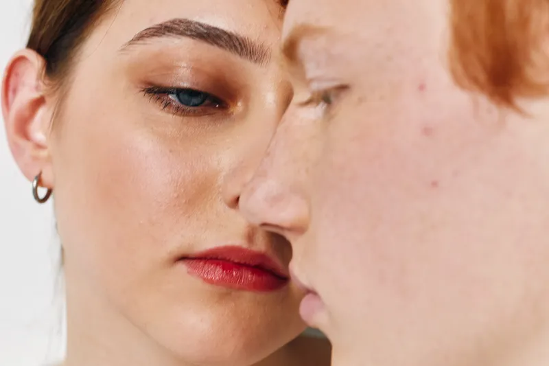 Closeup portrait of two young people with different skin tones showing natural beauty and diversity in facial features with serious calm expressions.