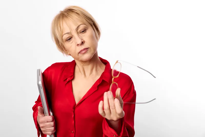 Woman senior red blouse holding glasses eyewear in studio portrait, calm expression, facing camera, soft light, white background