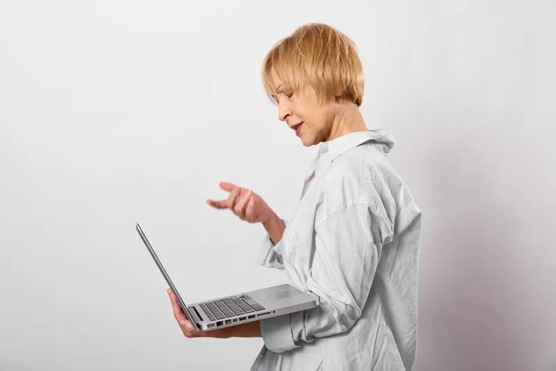 Child boy with blond hair using laptop, typing on keyboard, focused for education and learning, school study and technology concept, isolated on white background