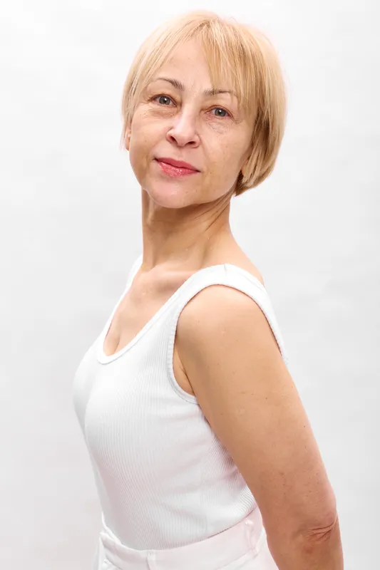 Senior woman portrait, blonde bob hair, gentle smile, standing on white studio background, calm mature beauty, soft light, close up shoulders, copy space, neutral face, relaxed