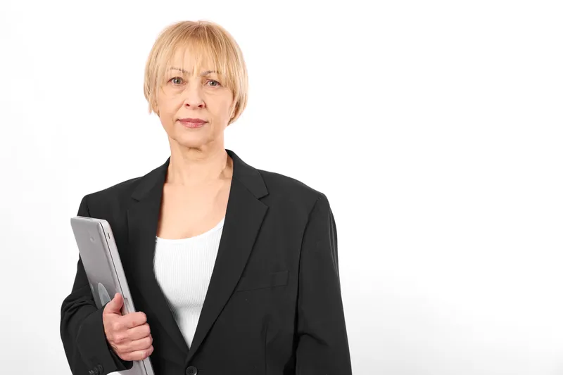 Elderly woman portrait in black blazer holding tablet, business technology and communication concept, confident office style, isolated on white background, adult digital device use for remote work