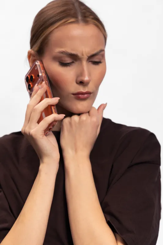 Young woman with serious facial expression talks on smartphone, holding hand near chin. Isolated on white background. Concept of communication, concentration, and decision making.