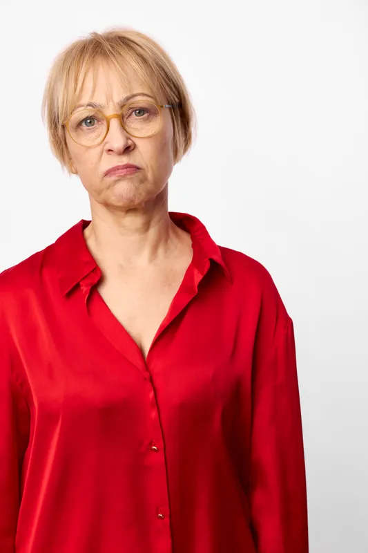 Woman glasses senior red blouse studio portrait serious expression, closeup mature face, white background, indoor light, elegant fashion, calm headshot