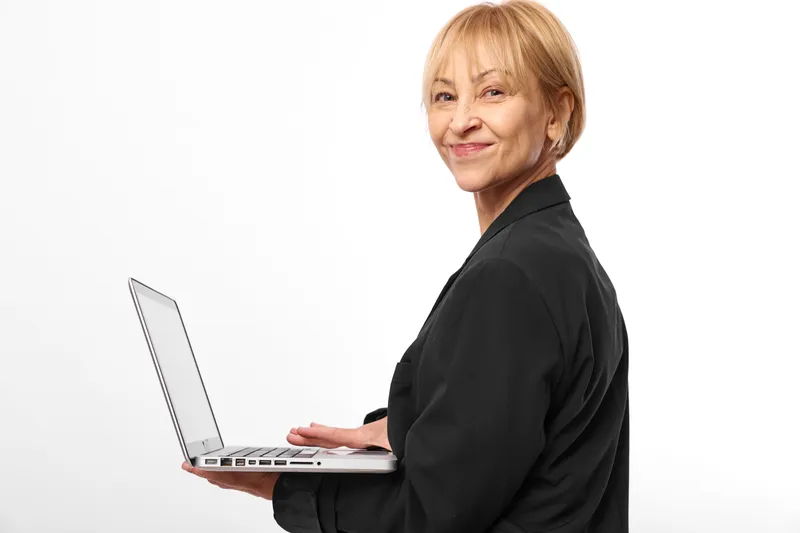 Smiling elderly woman, confident business portrait, clean black office jacket, holding laptop, technology work scene, remote communication success concept