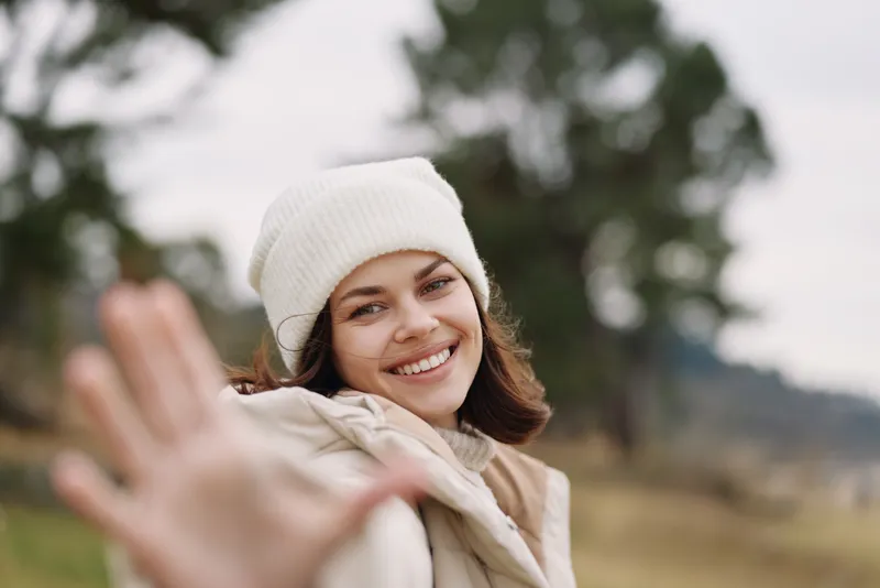 Woman smiling outdoor reaching hand portrait autumn casual kindness friendly moment in a field setting, captured in natural light with a candid, welcoming vibe