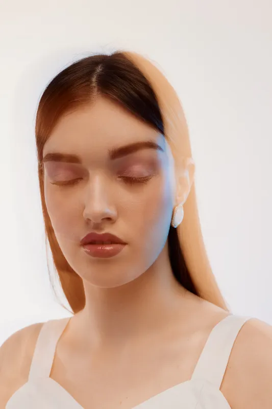 Young woman with closed eyes and smooth skin poses with a serene expression in soft lighting. Concept of beauty, fashion, skincare, and calmness in portrait photography.