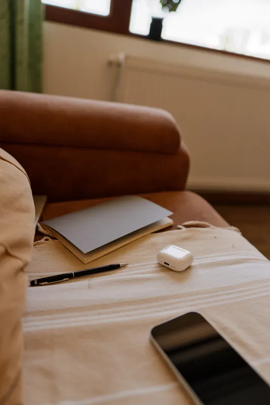 Cozy living room scene with a couch, coffee table, notebook and pen beside a smartphone, captured in natural light for a relaxed lifestyle and home ambiance.