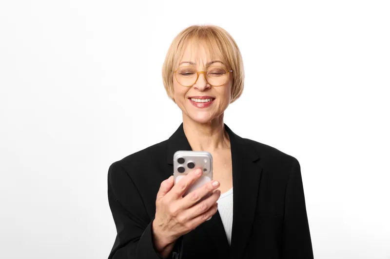 Woman smartphone glasses blazer smile communication technology portrait business senior, mature woman holds smartphone, smiling, black blazer, isolated on white background, close up