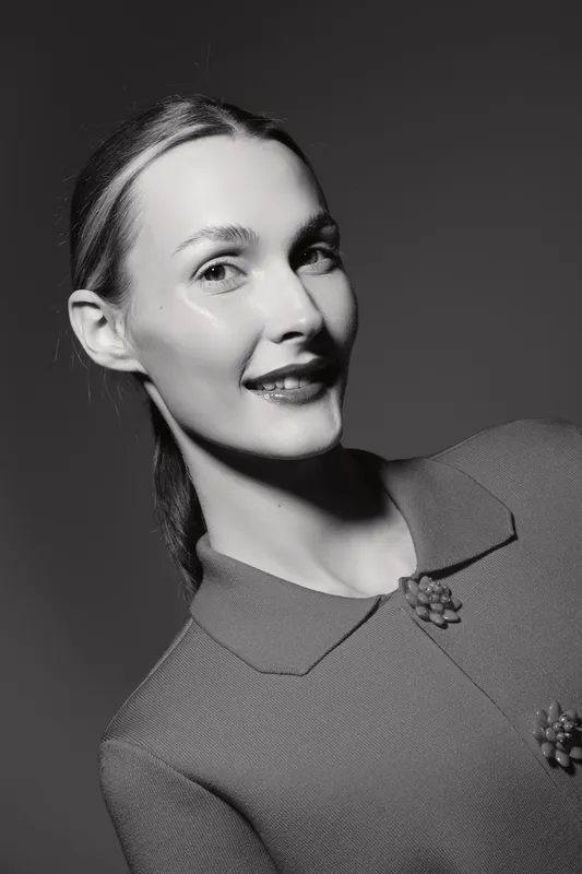 Portrait of a smiling Caucasian woman with light skin and brown hair in a vintage style dress. Black and white studio photography.