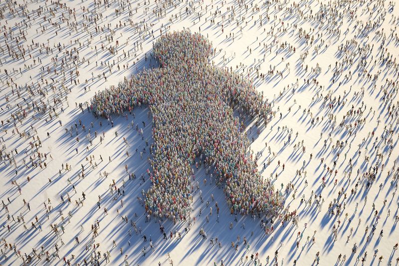 Aerial view of thousands of people assembled into a giant upward arrow on a bright snowy plain, their long shadows stretching across the surface, symbolizing unity, direction and progress.