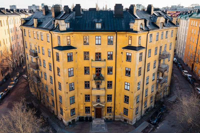 Aerial view of a historic yellow apartment building forming a curved courtyard, surrounded by narrow streets and bare trees, highlighting urban residential architecture and textured facades.
