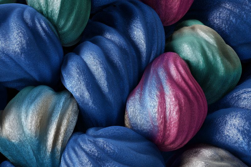 Close-up view of vibrant silky fabric bundles with twisted textures and metallic sheen, displaying rich jewel tones and intricate folds that form an abstract textile pattern for design.