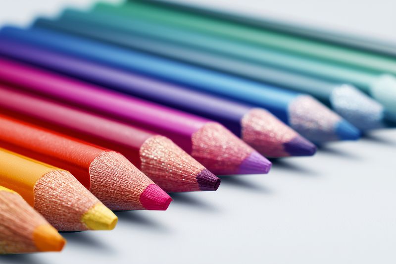 Close-up view of colorful sharpened colored pencils carefully aligned diagonally across a soft light background, showcasing wooden textures and vibrant pigment tips for creative and educational