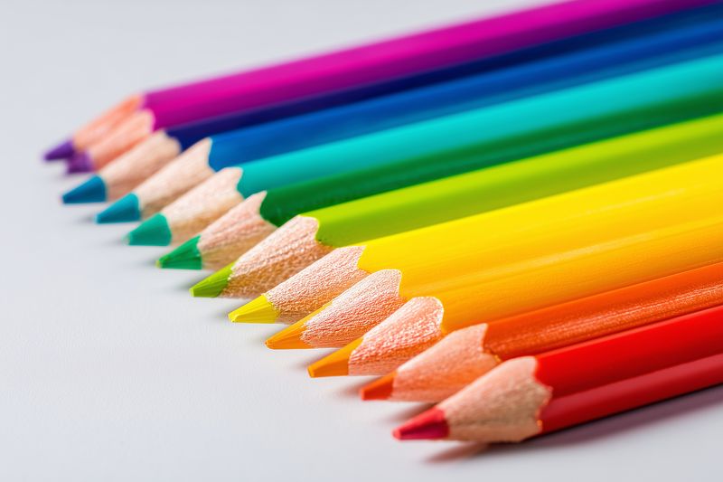 Close-up of sharpened colored pencils arranged diagonally on a white background, highlighting vibrant hues and wooden textures ideal for art, design, education and creative projects.