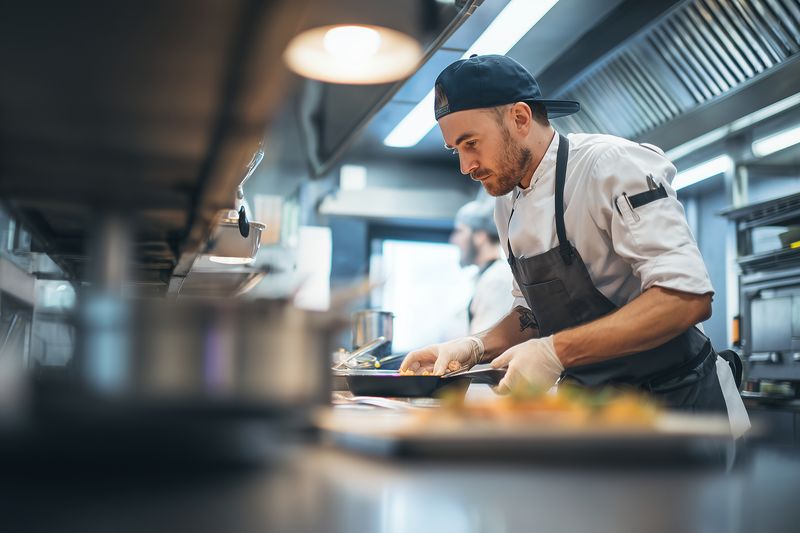 Professional chef plating elegant dishes in a busy commercial kitchen, focused on precise presentation and fresh ingredients while preparing meals for restaurant service and fine dining.