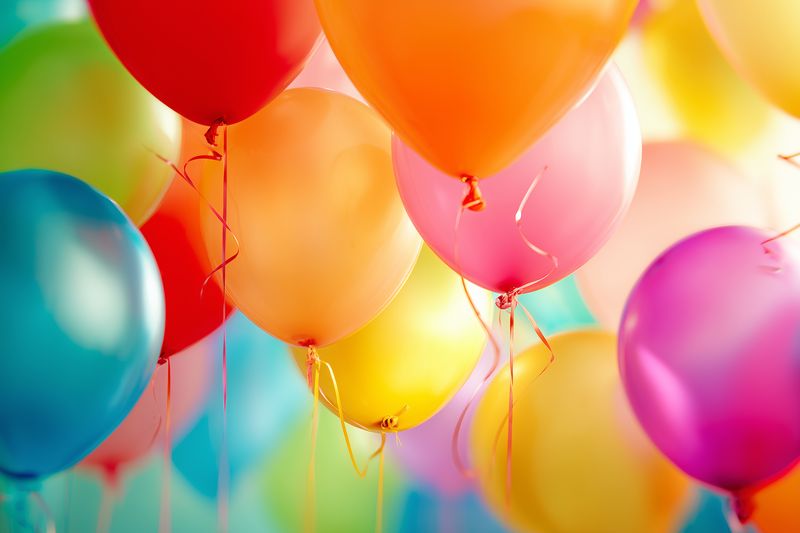 Bright colorful helium balloons filling the frame, glossy latex surfaces reflecting light and creating a festive atmosphere for celebrations, parties, and joyful gatherings.