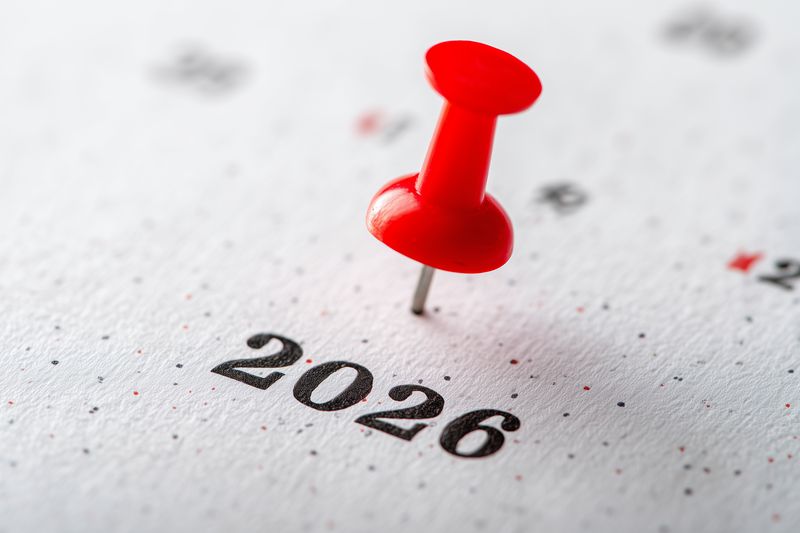 Close-up of a red pushpin marking the year 2026 on a printed calendar, symbolizing planning, future deadlines, appointments and goal setting with a sharp shallow depth of field.