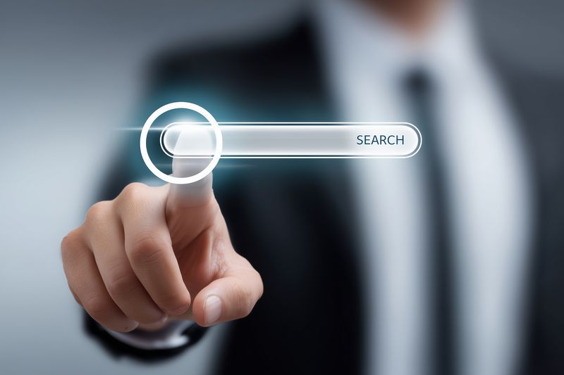 A professional businessman in a suit touches a transparent virtual search bar on a digital interface, illustrating modern touchscreen interaction, online search and technology concept visualization.