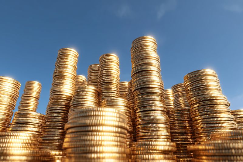 Coins gold wealth finance stack economy, piled shiny golden coins stacked in tall towers against blue sky, savings investment concept for banking prosperity growth