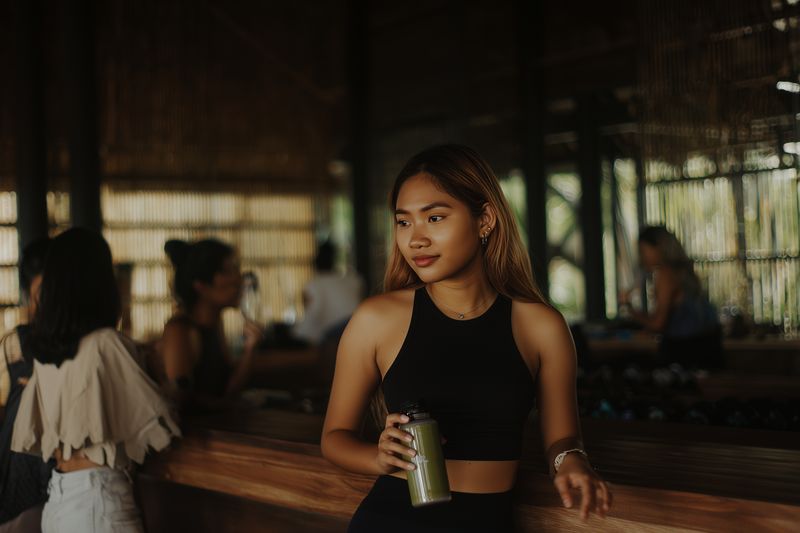 Woman cafe bar drink casual summer smile beverage relaxed interior lifestyle young coffee cup standing leisure light warm indoor restaurant outfit black top urban style