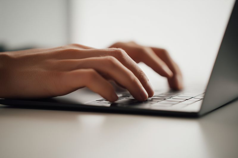 Hands keyboard typing laptop workspace desk close up of fingers on keys in workspace for remote work digital communication focused on computer typing emails and office tasks